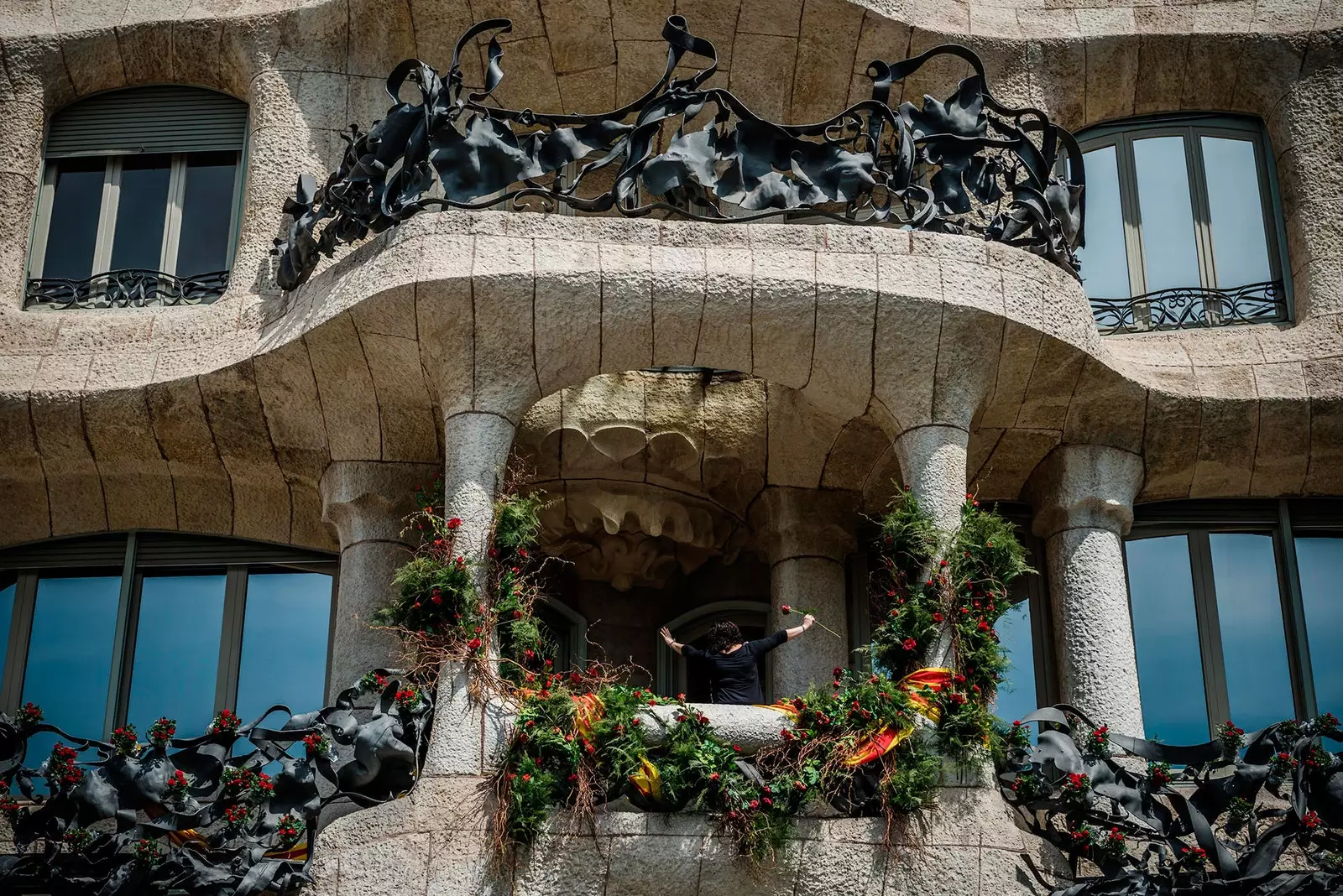 Žena podiže ružu na jednom od balkona Casa Batlló