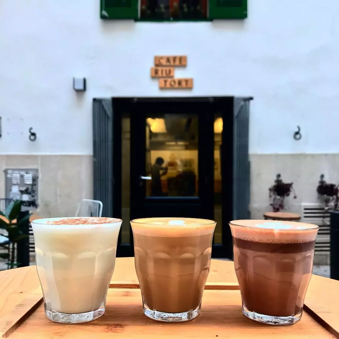 Cupáin le caifeanna éagsúla ag doras Café Riutort i Palma de Mallorca.