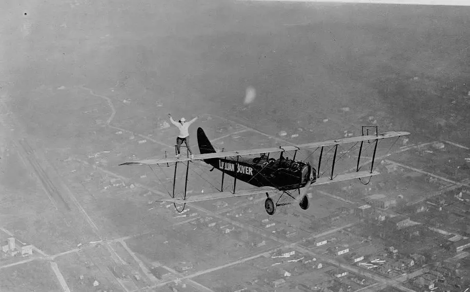 Een 'Wing Walker' die aerobatics doet op de vleugel van een vliegtuig