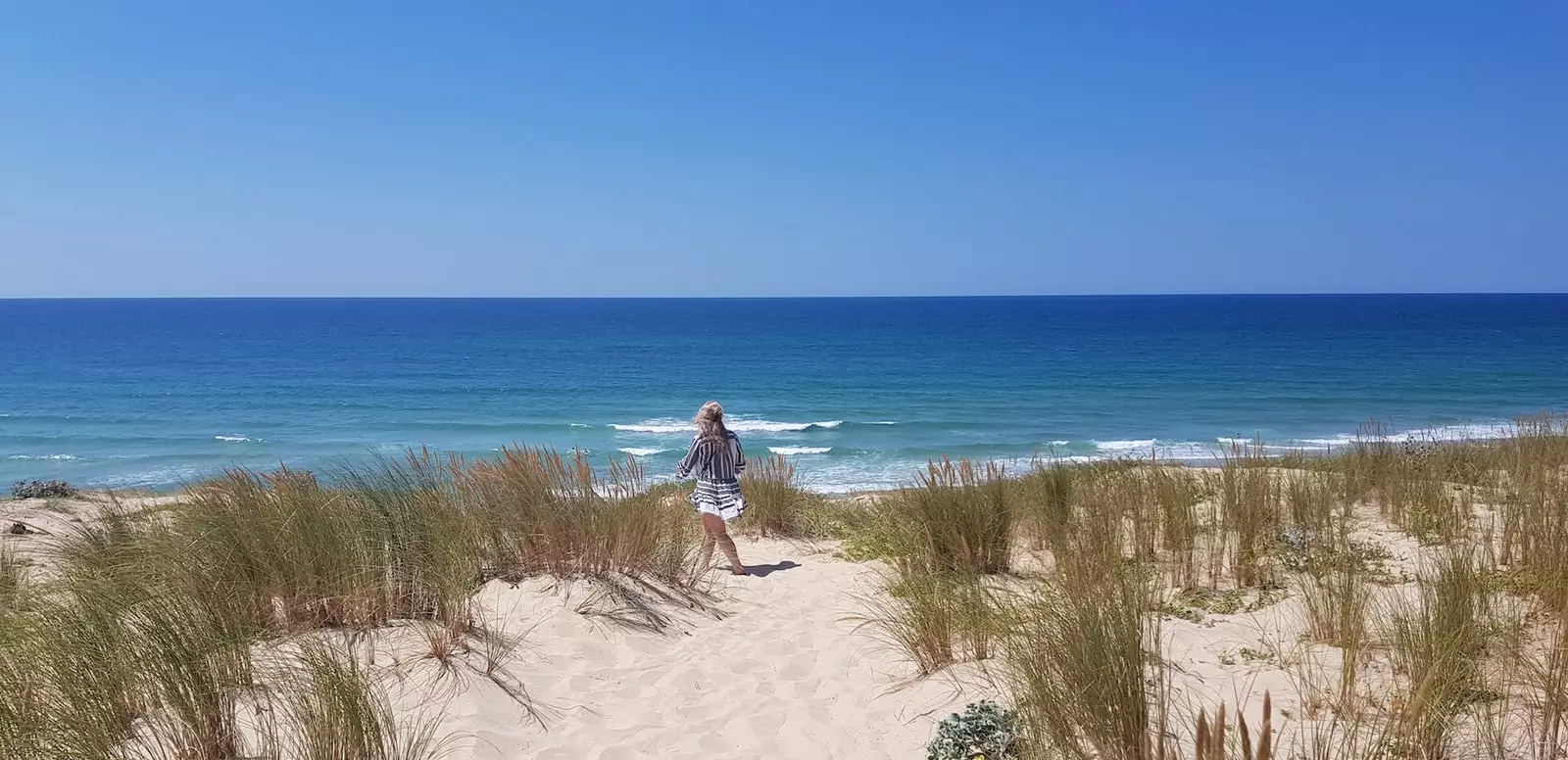 Wanita berjalan di sepanjang pantai Cap Ferret