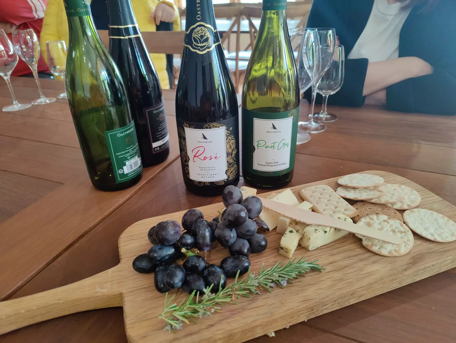 Vinhos locais acompanhados de bolachas, queijos e uvas na degustação.