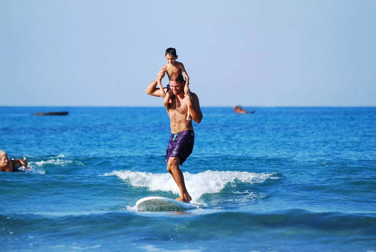 Pai e filho surfando em uma prancha