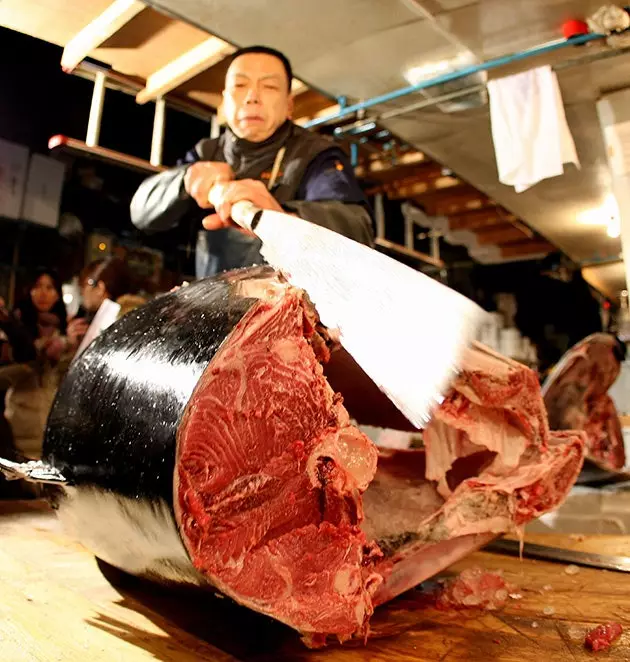 A worker cuts the back of a tuna