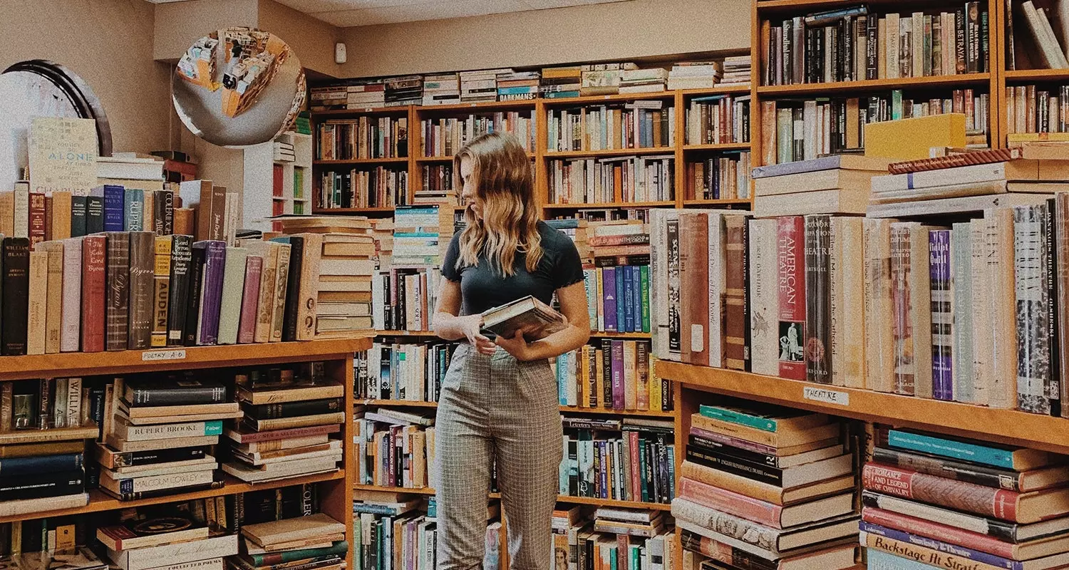 Fille avec des livres dans une librairie