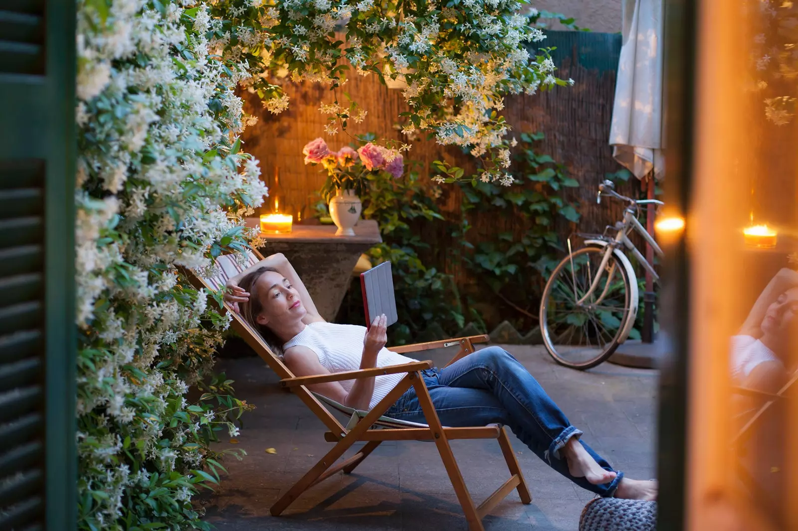 Donna che legge in un giardino pieno di fiori