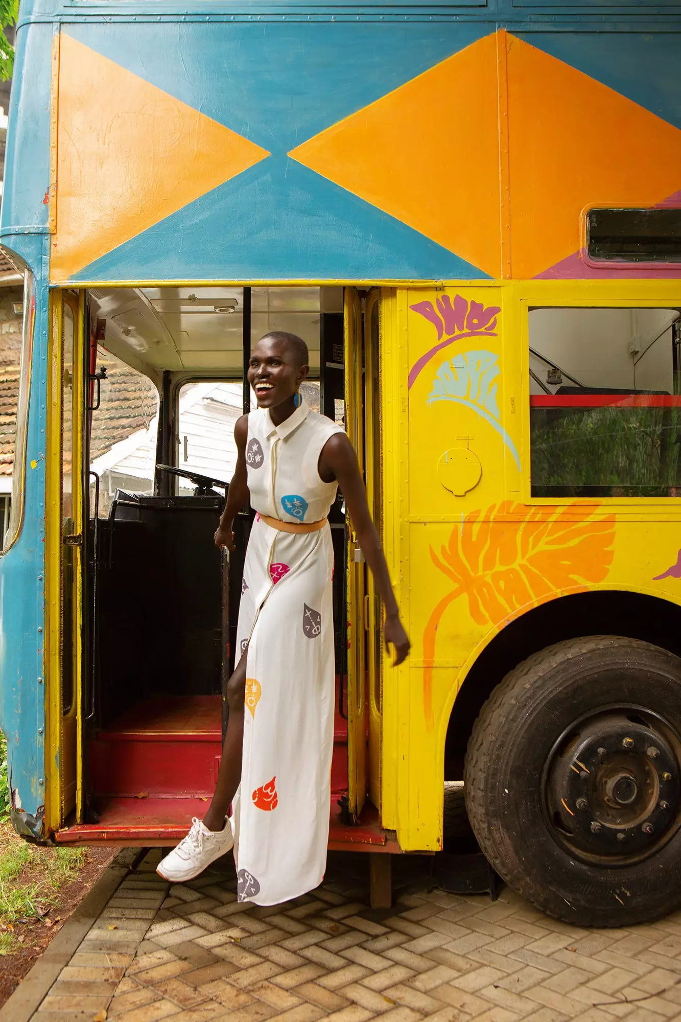 Ajuma deixando The Bus em um vestido de camisa Mille Collines com motivos Swahili em uma versão pop