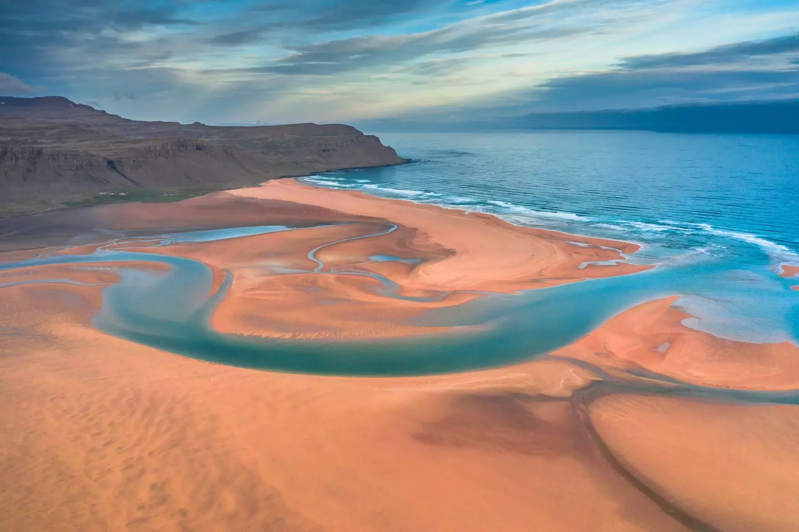 Droneutsikt fra den islandske Raudasandur-stranden med blå vannbekker og gul sand