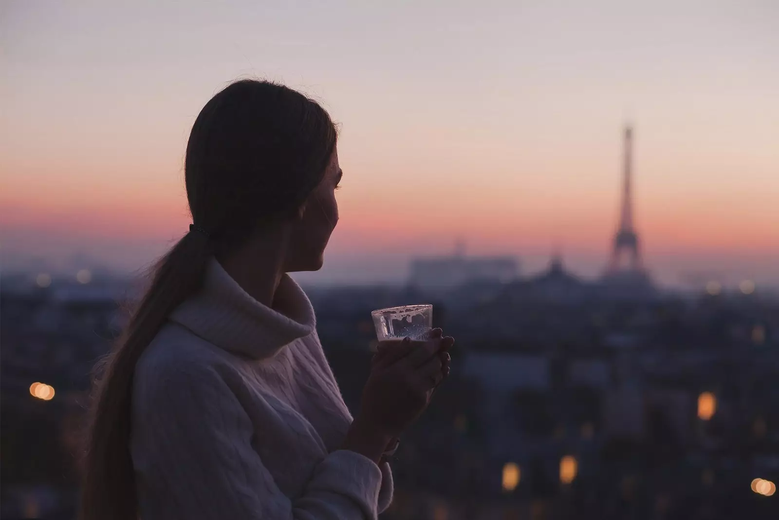 stelpa að drekka kaffi fyrir framan Eiffel turninn