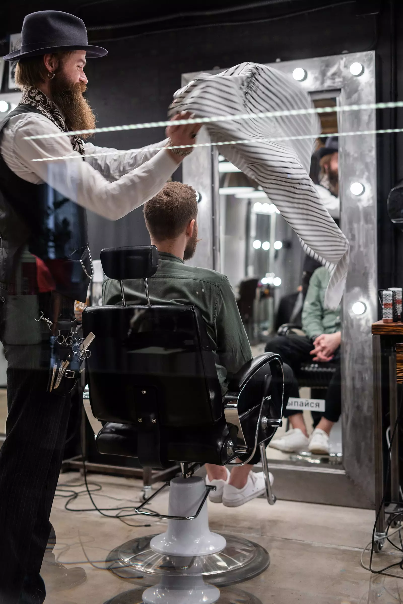 Um cabeleireiro está prestes a cortar o cabelo de um homem em uma barbearia