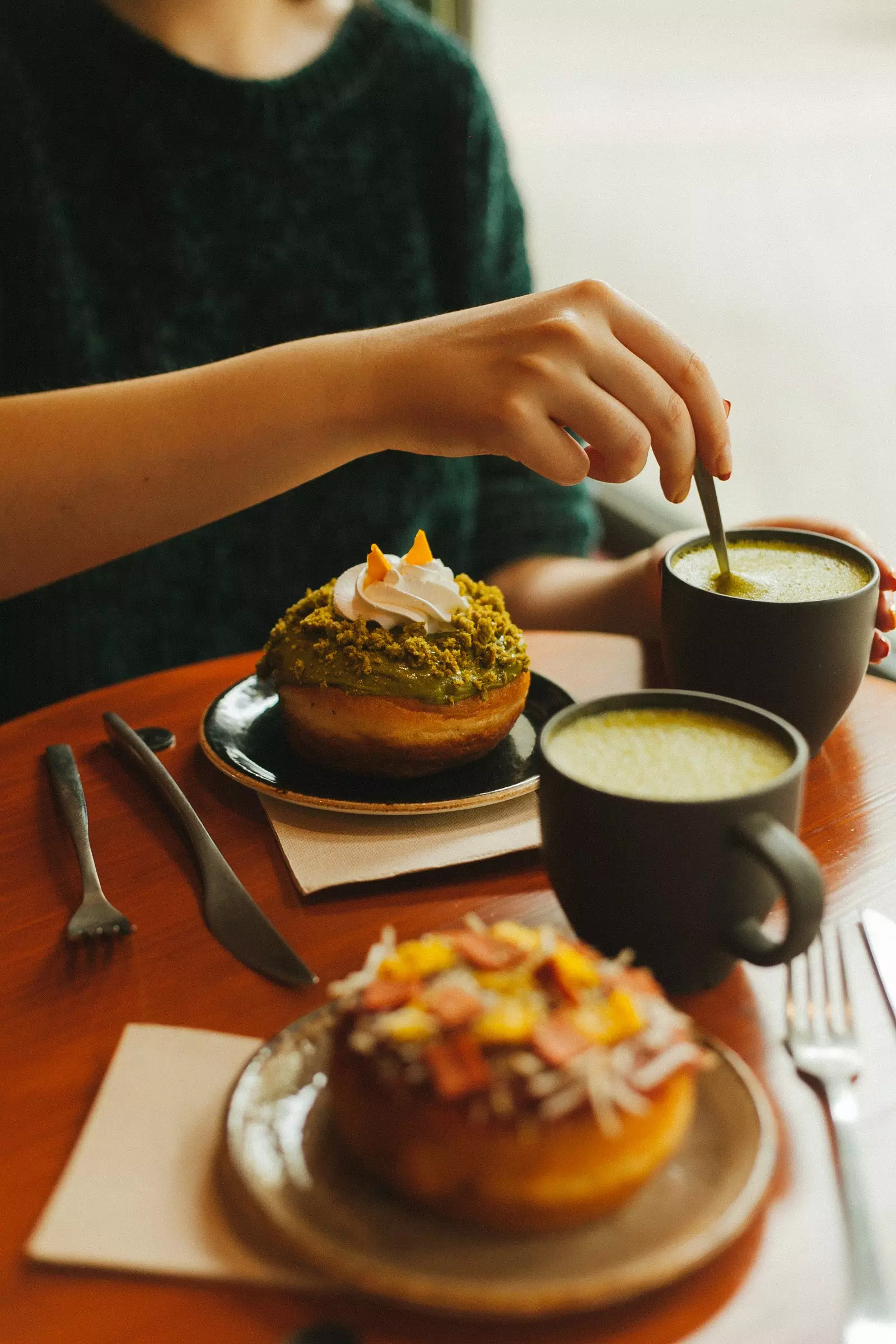 Пикантный пончик и сладкий пончик рядом с двумя чашками латте матча в Bite Me Café