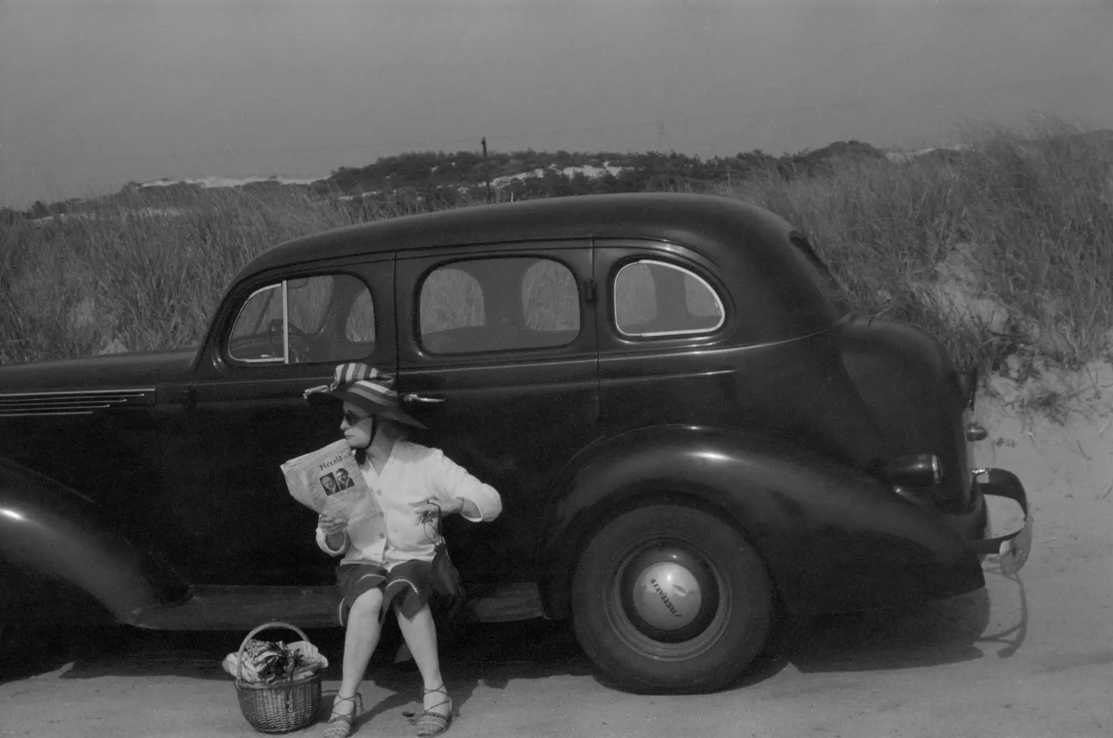 1940年代、プロビンスタウンのビーチで車の横で休む女性