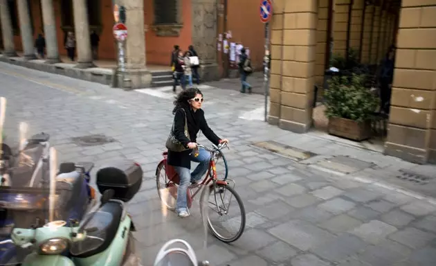 En cyklist cyklar genom arkaderna i Bologna