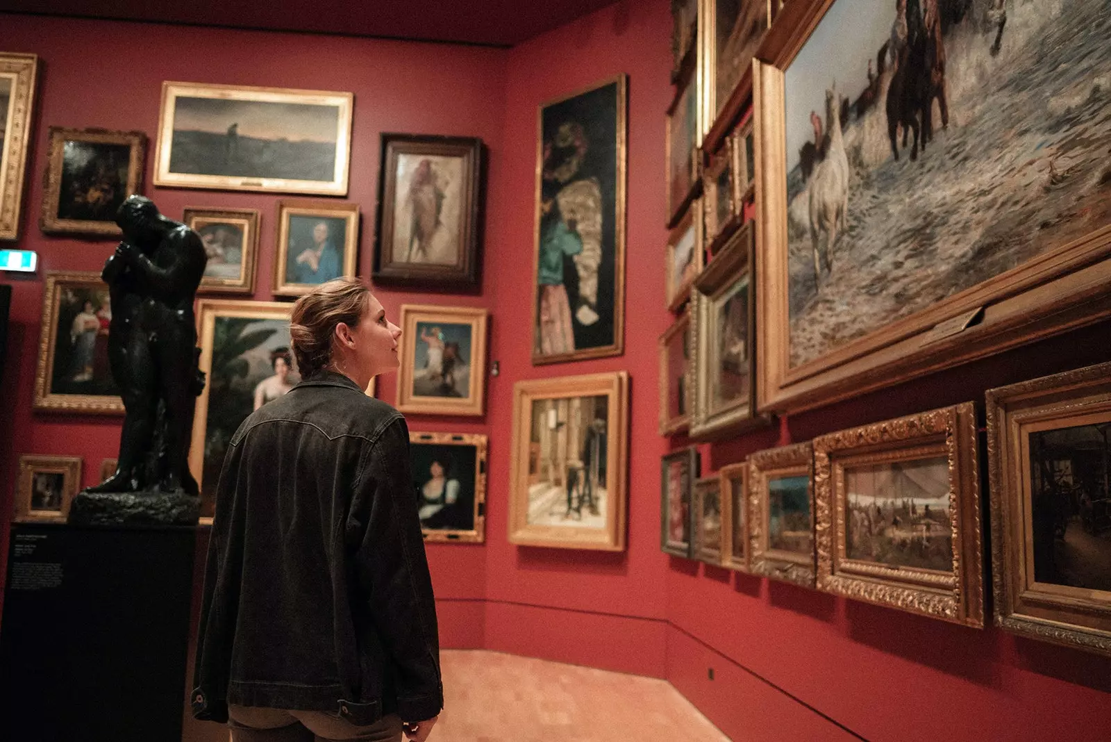 Woman contemplating paintings in museum