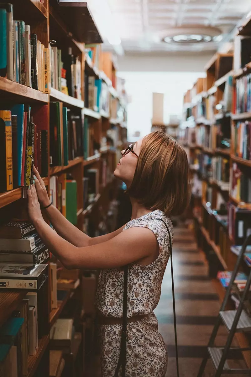 Vrouw op zoek naar een boek in een van die boekwinkels die de ziel redden