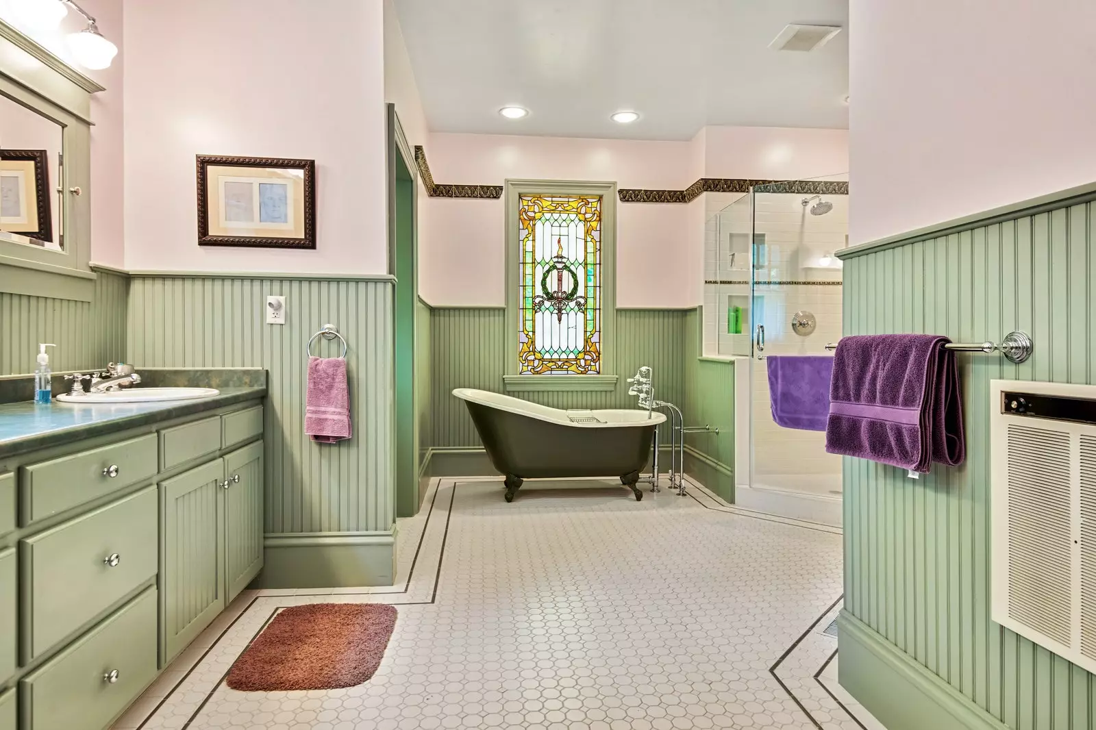 Luxurious green decorated bathroom with free standing tub shower and stained glass window overlooking Brant Lake .