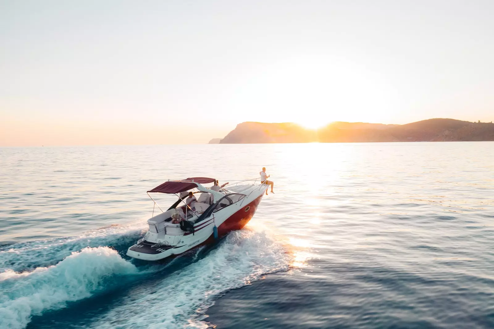 Yachtsegeln bei Sonnenuntergang mit Bergen im Hintergrund