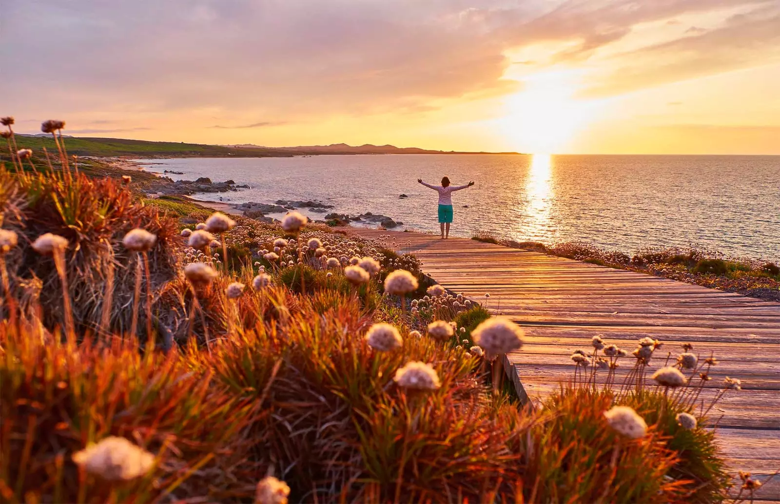 Dame, die bei Sonnenuntergang neben dem Strand spazieren geht