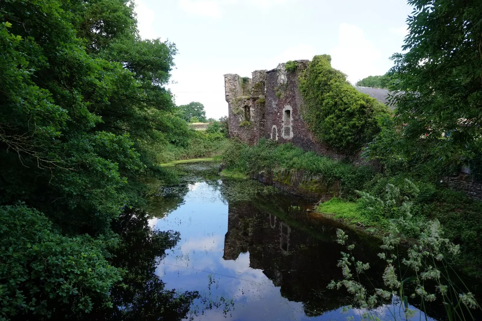 Remains of a 14th-century castle built with local red stone are preserved on the property.