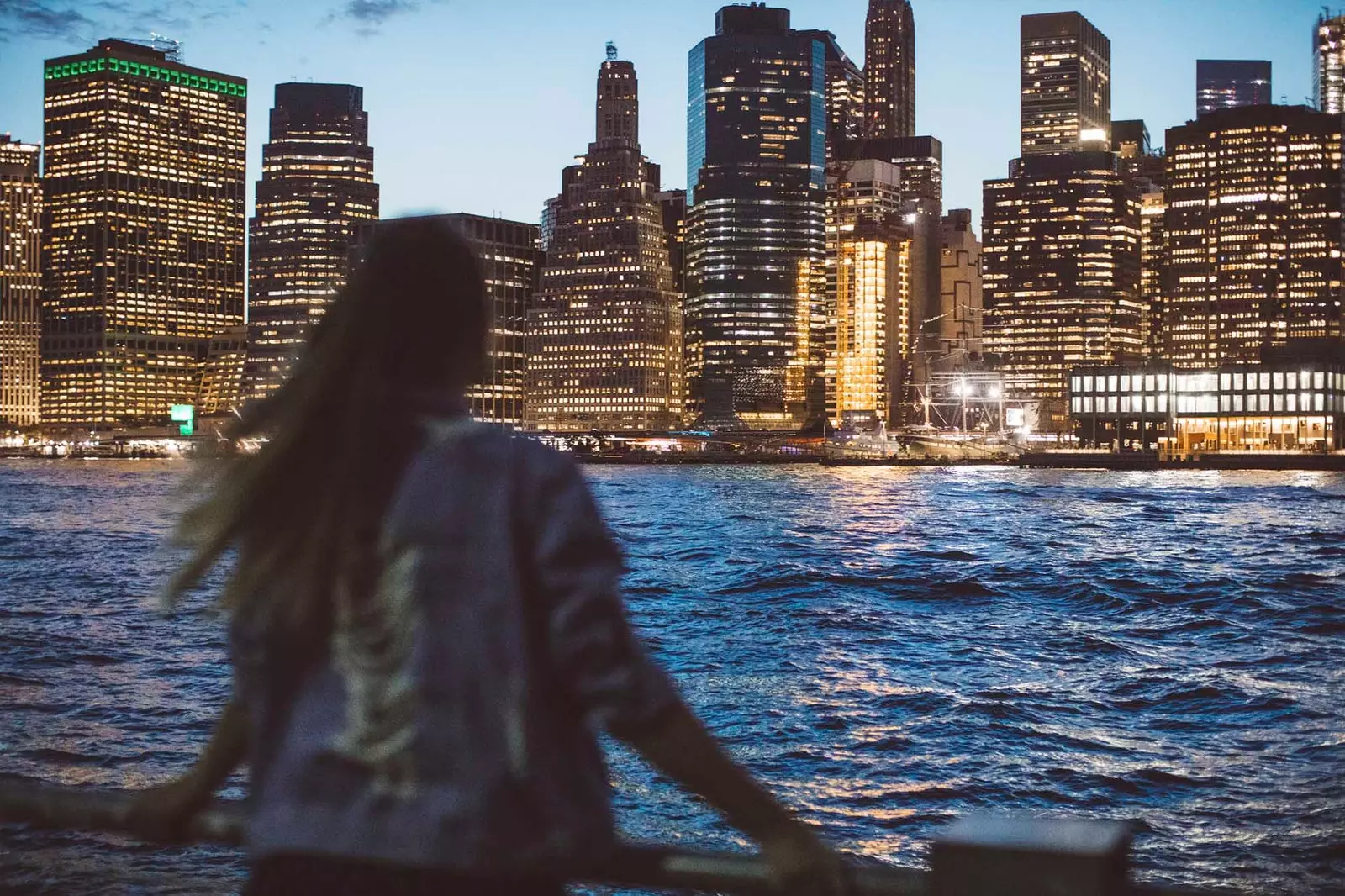 meisje dat 's nachts naar de skyline van new york kijkt