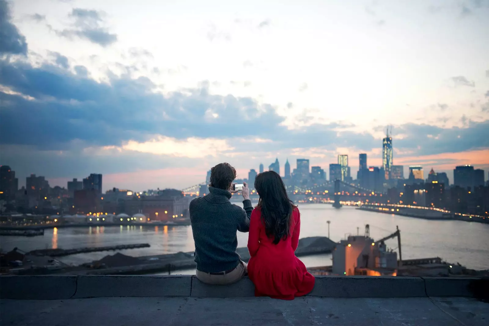 Paar sitzt im Sonnenuntergang und schaut auf das Handy