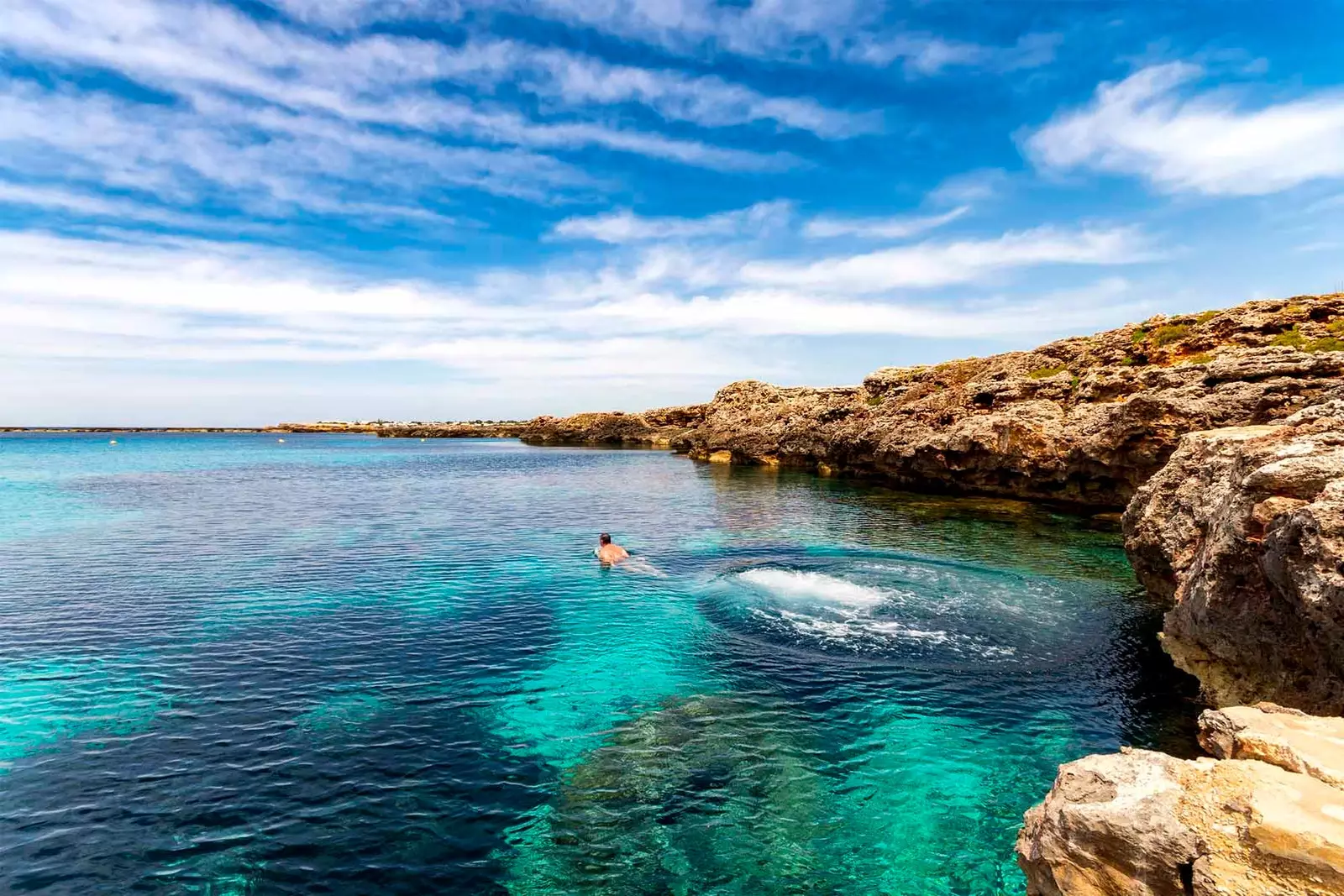 man simmar i havet på menorca