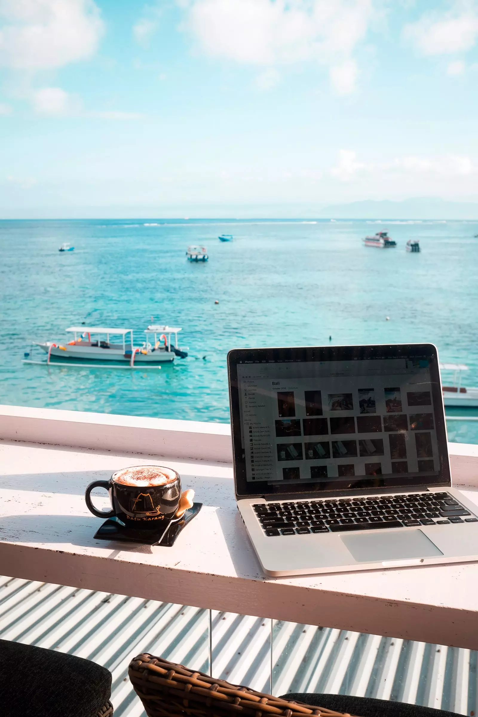 Laptop og kaffe foran et blått hav i Indonesia