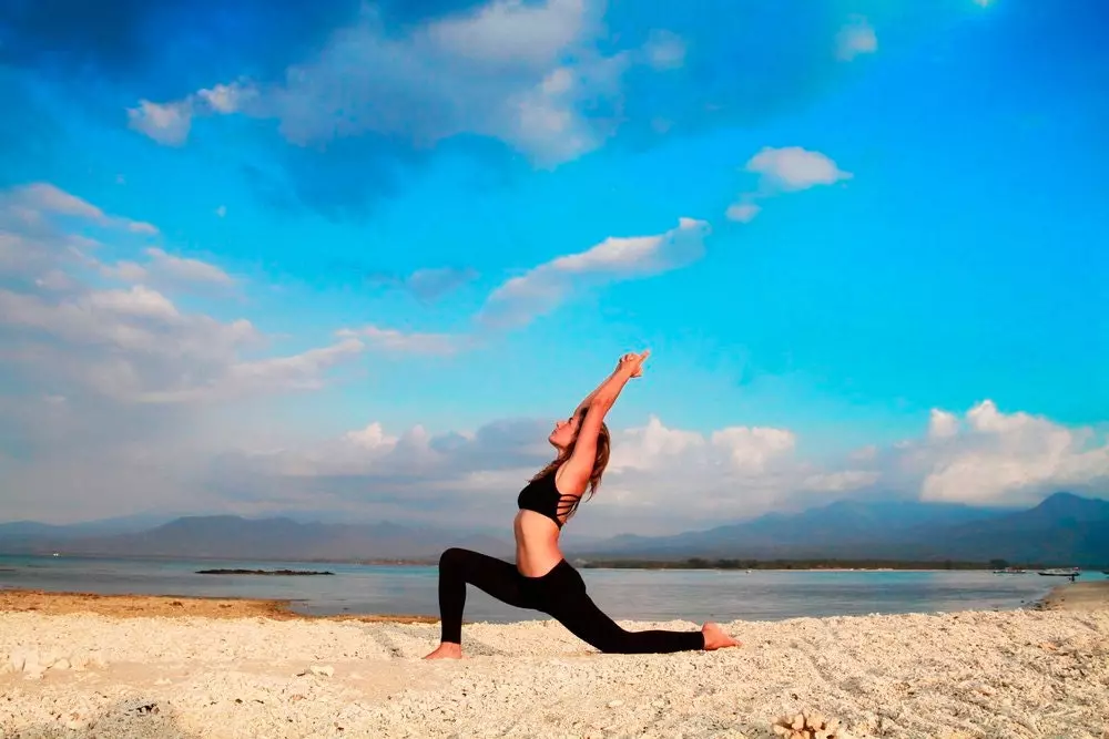 cailín ag déanamh Yoga os comhair na farraige