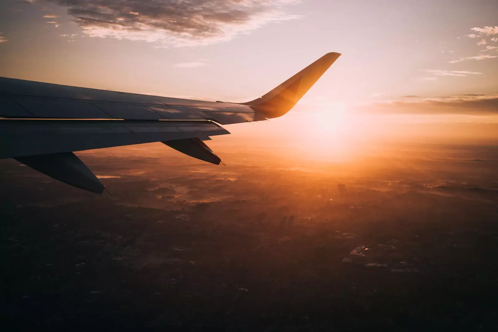 Aereo che vola al tramonto sopra le nuvole arancioni.