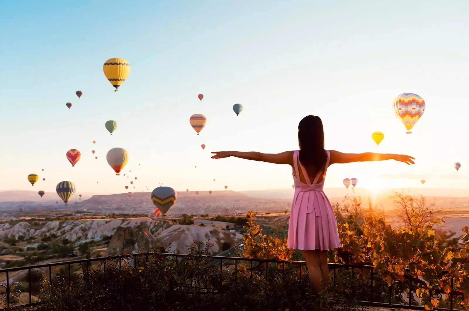 Mädchen, das den Sonnenuntergang mit Heißluftballons beobachtet