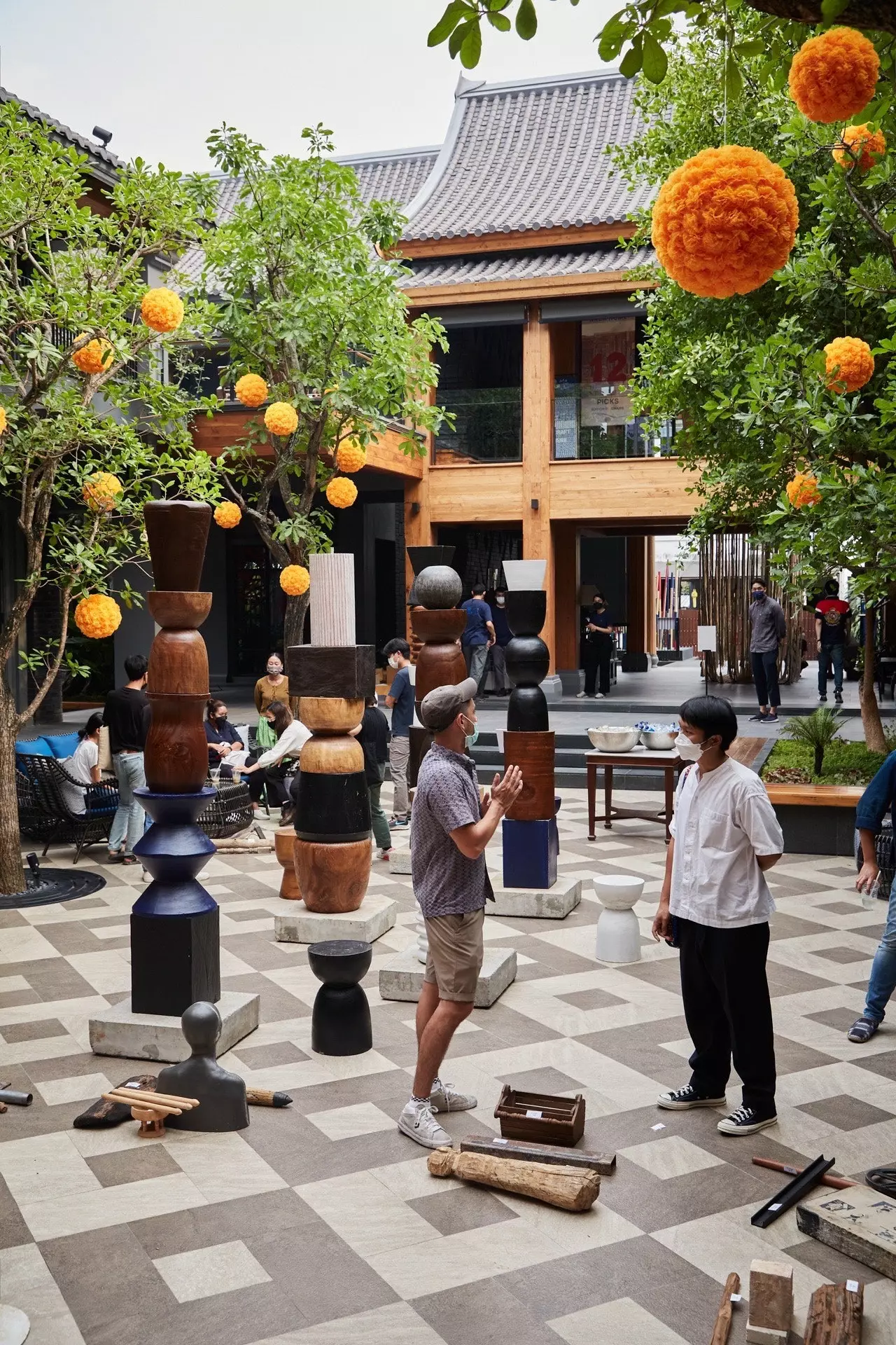 Exposição de esculturas no pátio da Kalm Village entre as árvores decoradas com lanternas de papel.