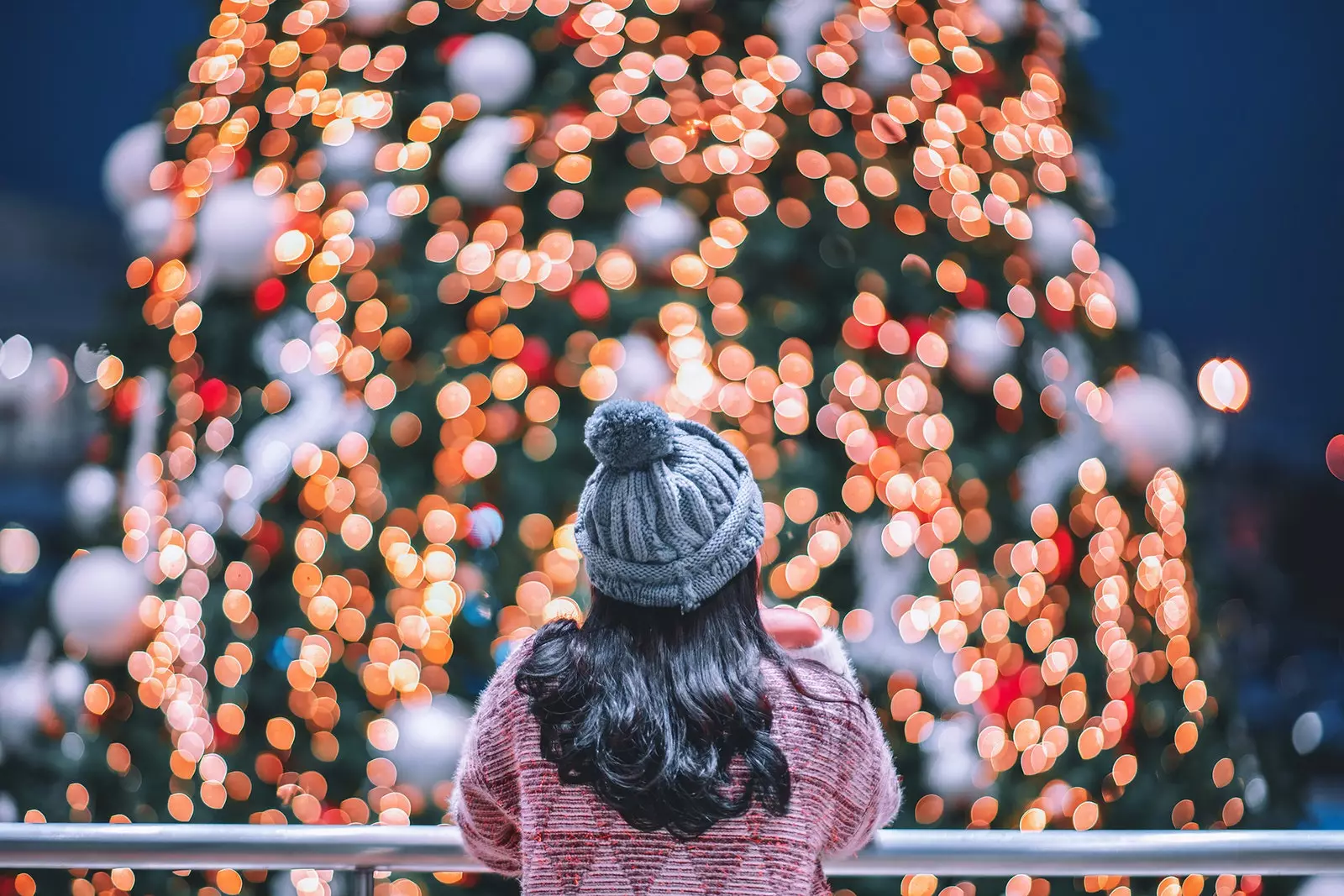 Wanita merenungkan lampu pohon Natal