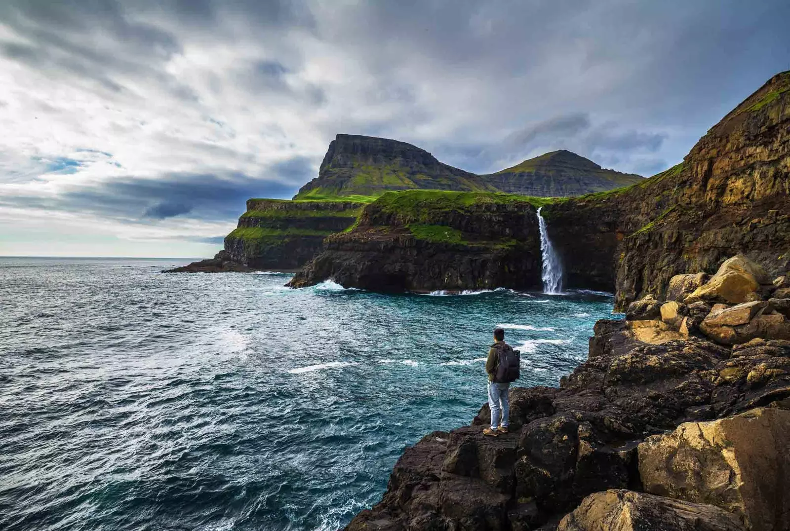 boy looking at waterfall in faroe islands