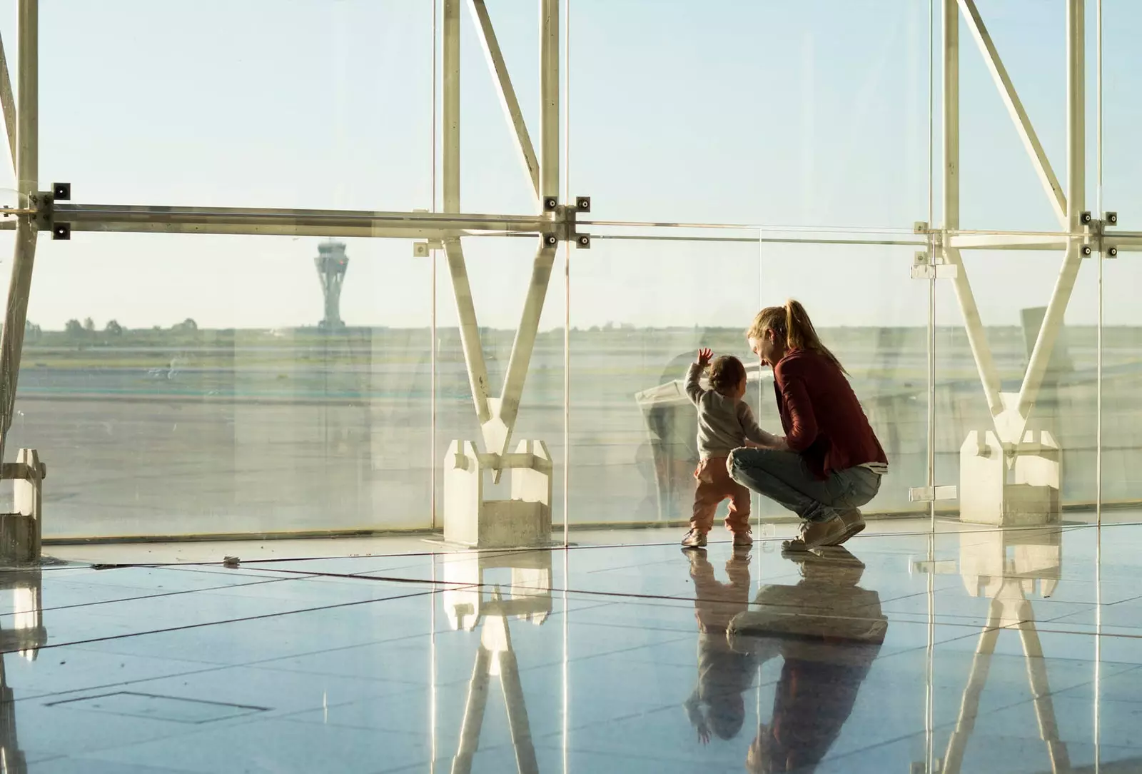 Frau und Sohn schauen aus dem Fenster des Flughafens Barcelona