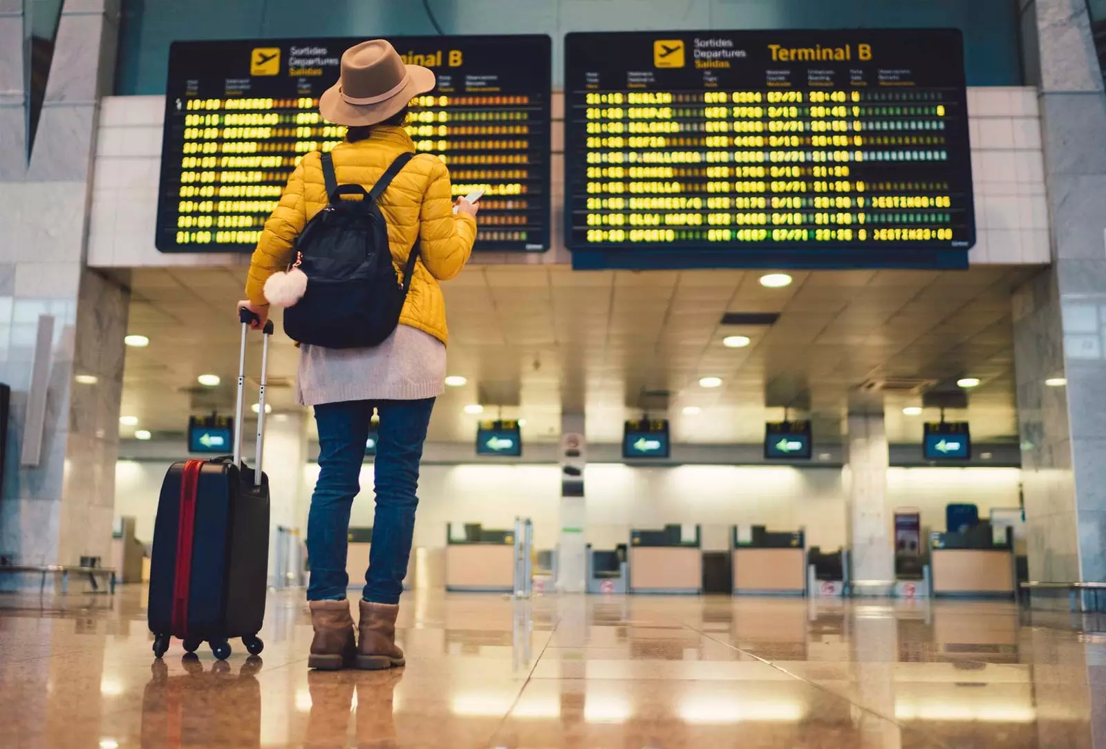 viajante feminino olhando para placa de partida no aeroporto