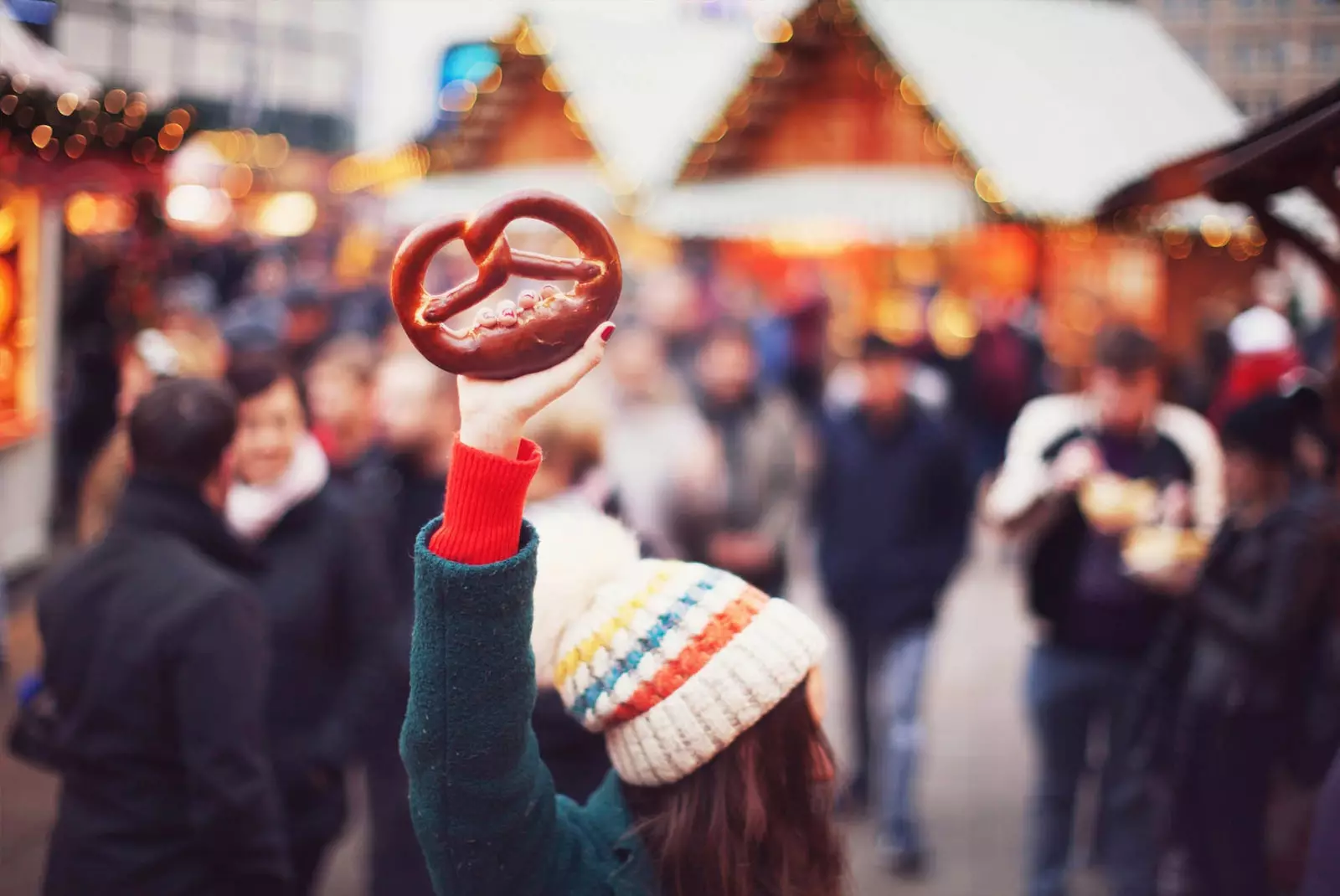 mädchen, das eine brezel am weihnachtsmarkt anhebt