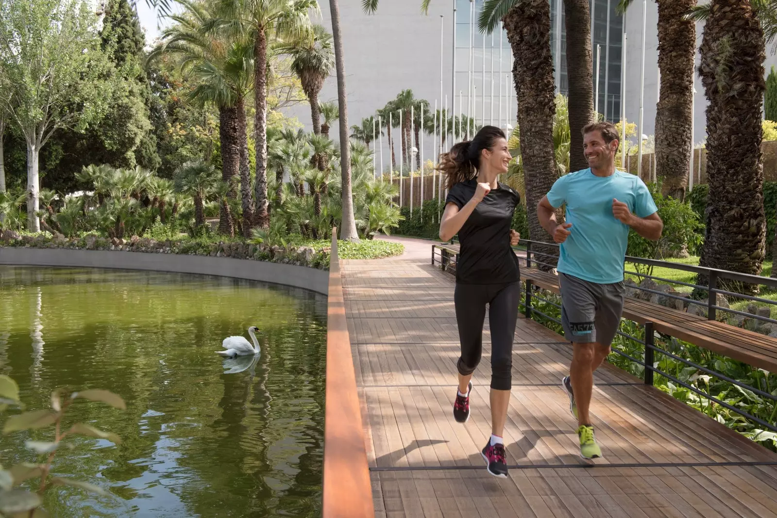 Duas pessoas correm ao lado de uma lagoa no Hotel Fairmont Barcelona