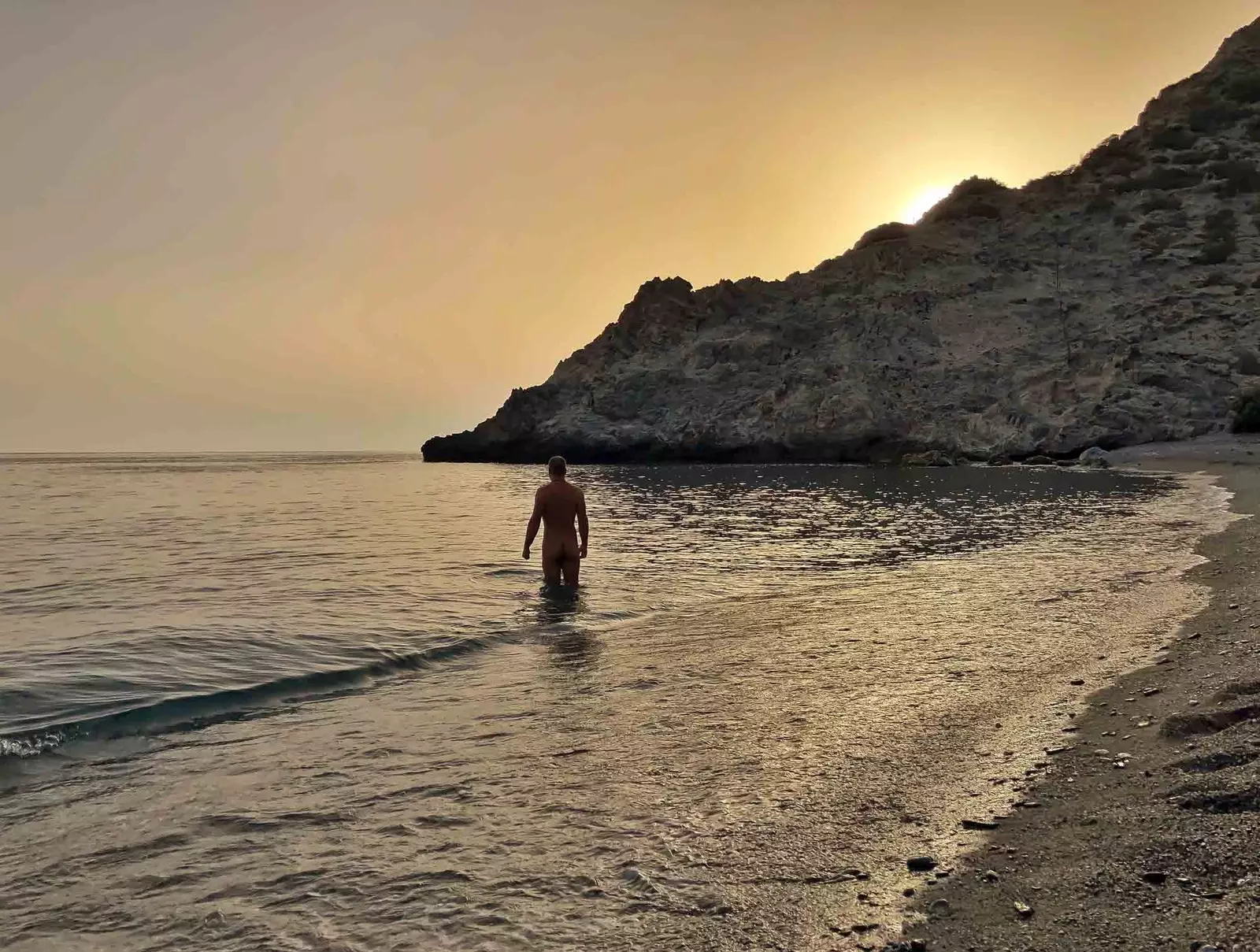 home d'esquena nu a platja de cantarrijan al capvespre