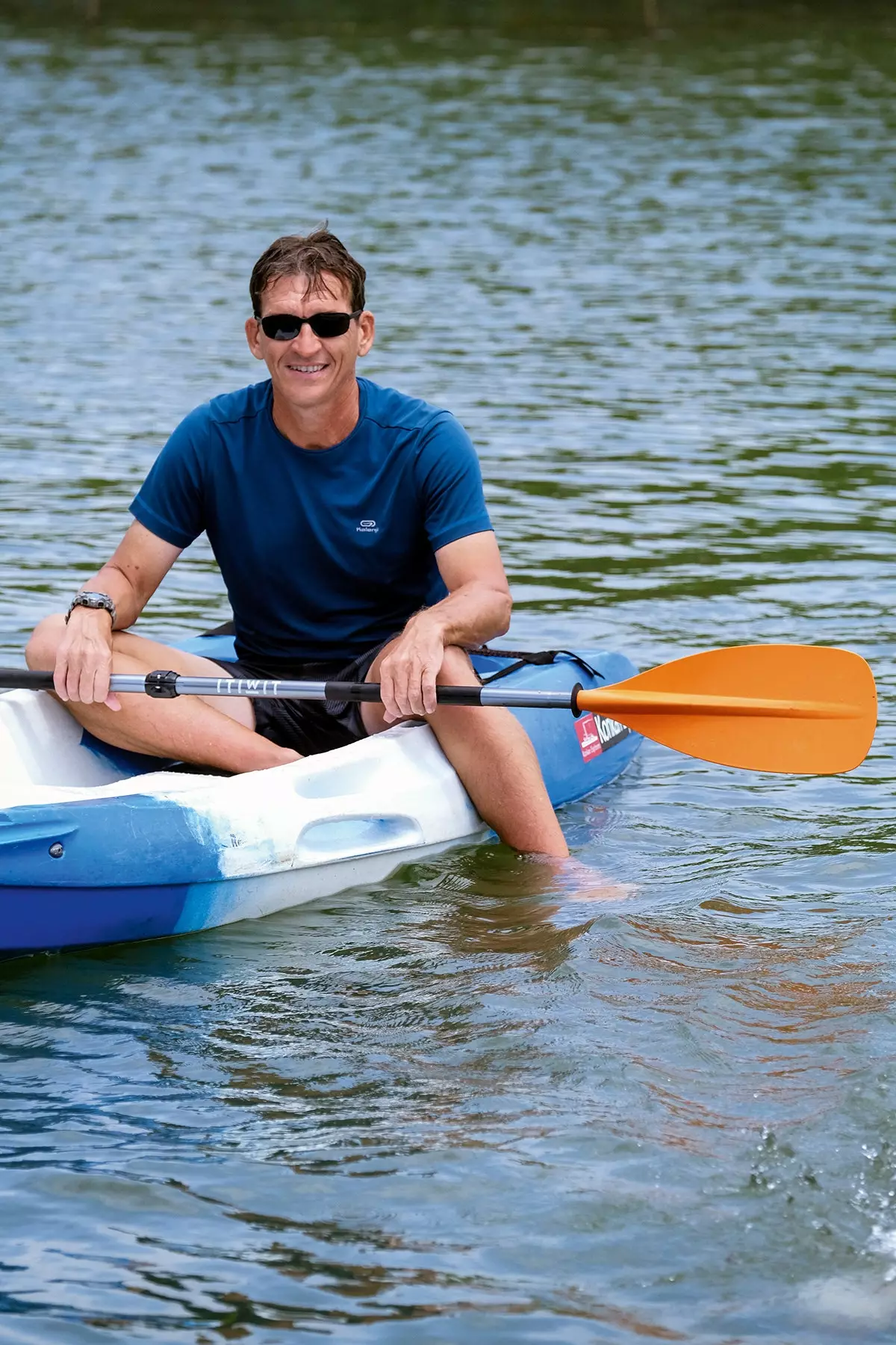 Uomo sorridente su un kayak con una pagaia