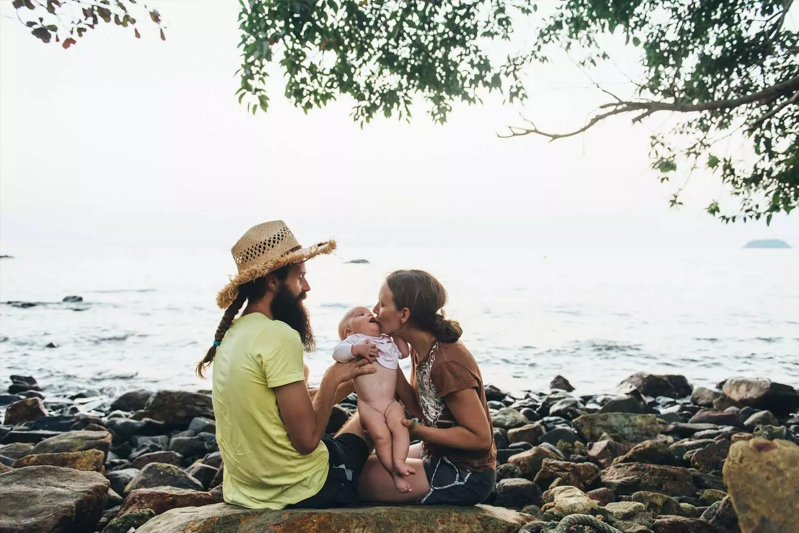 coppia su una spiaggia che abbraccia un bambino