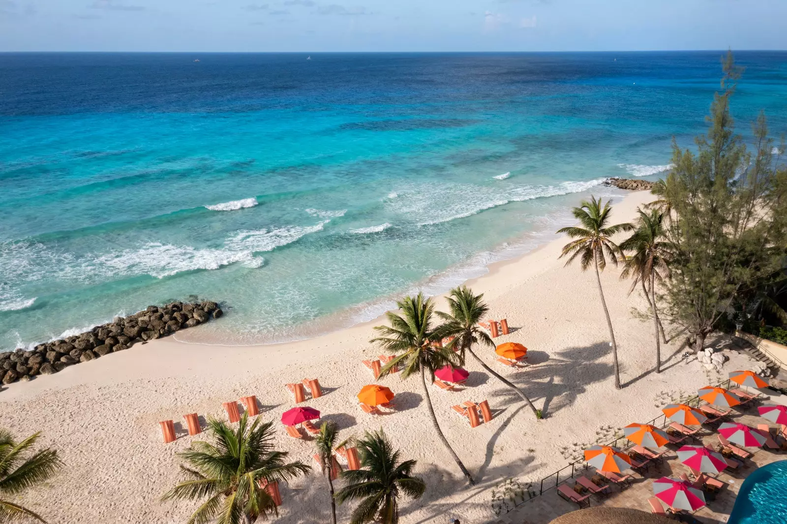 Strand mit Palmen, Liegestühlen und Sonnenschirmen mit dem Meer im Hintergrund