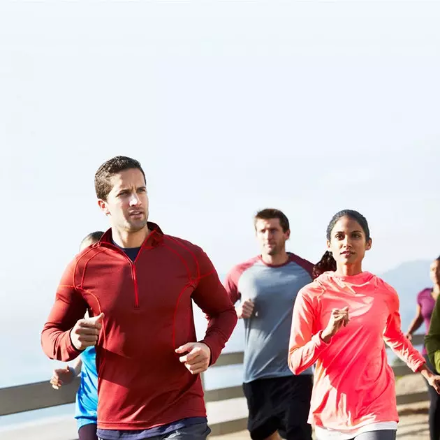 Grupo de pessoas em roupas esportivas correndo sob o céu azul