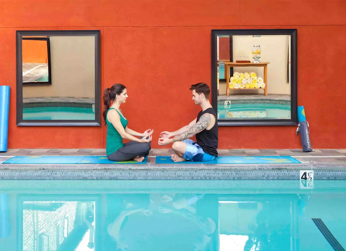 Duas pessoas em meditação posam à beira de uma piscina no Kimpton Hotel