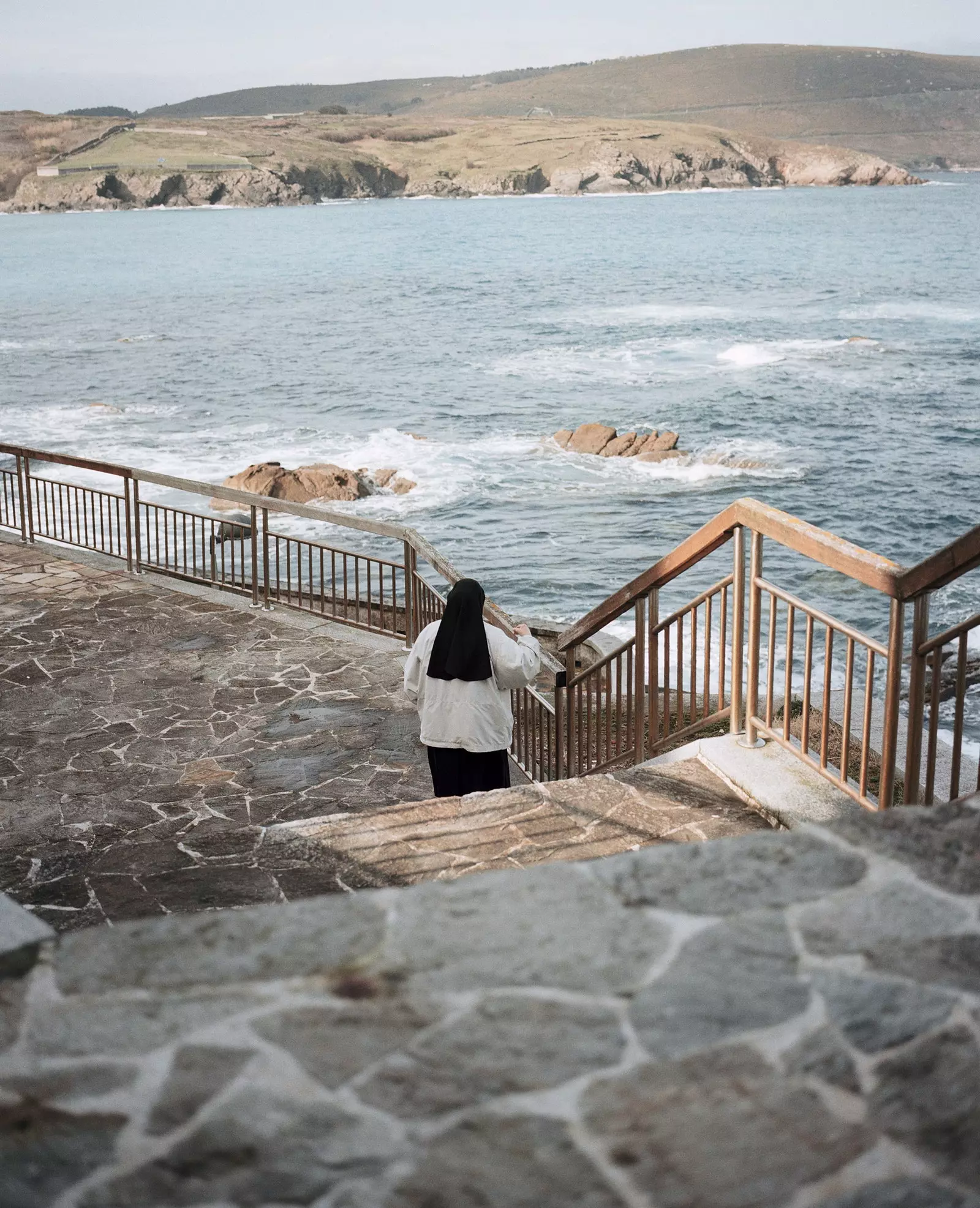 Uma freira caminha ao longo do cais da vila piscatória de Malpica