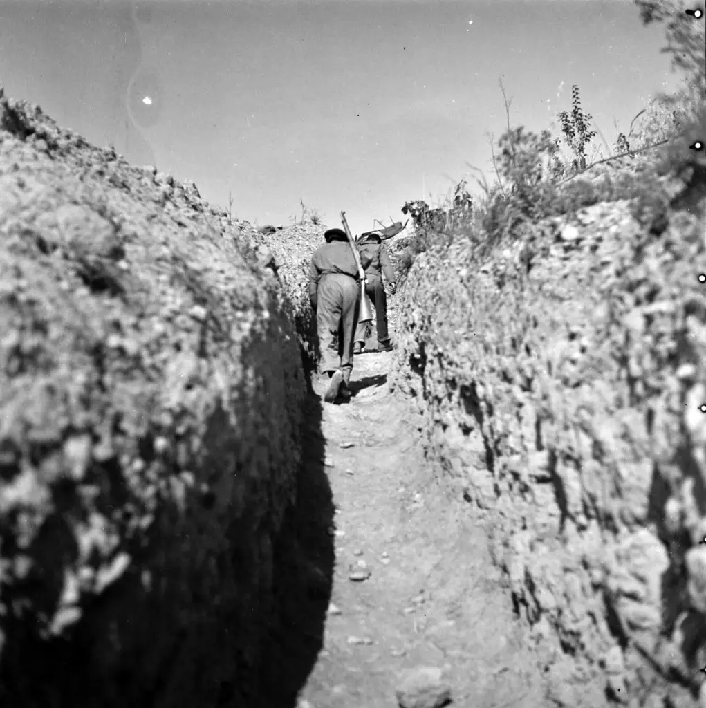 Black and white photograph from 1937 of two soldiers walking through a trench on the Aragón Front.