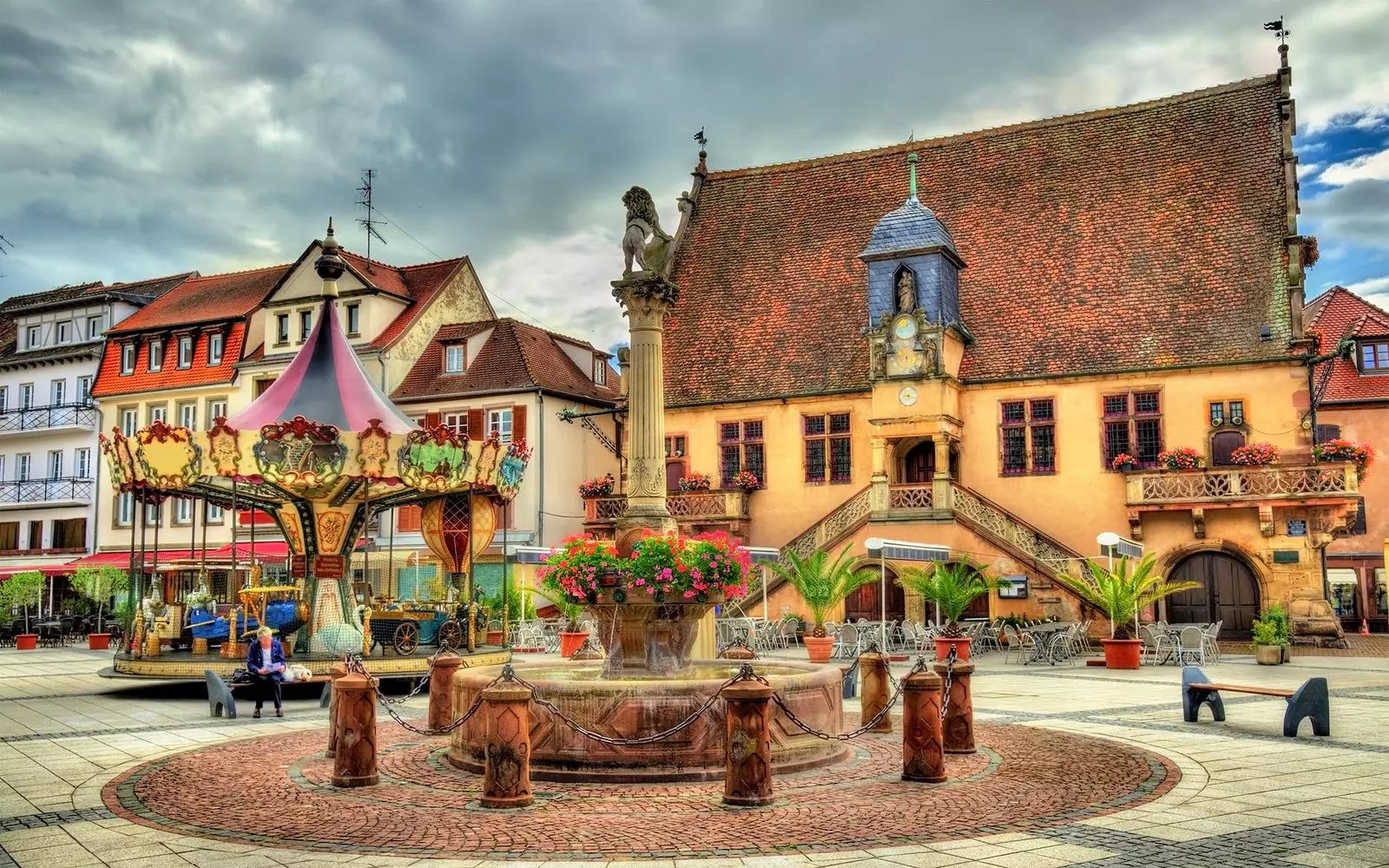 Praça Molsheim com suas casinhas coloridas, carrossel e fonte com flores.