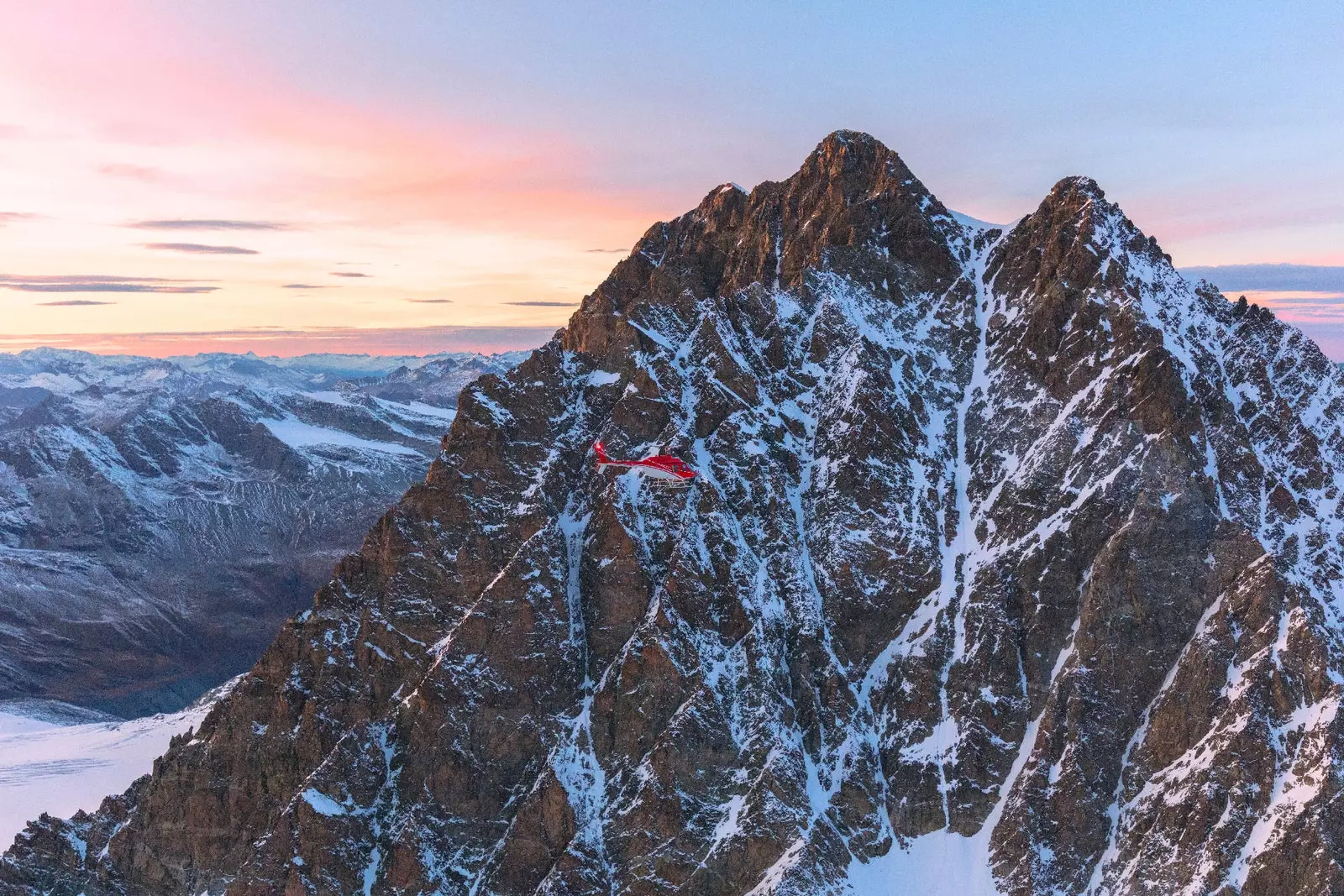 Fotografia delle Alpi svizzere spolverate di neve e di crepuscolo dietro le cime frastagliate.