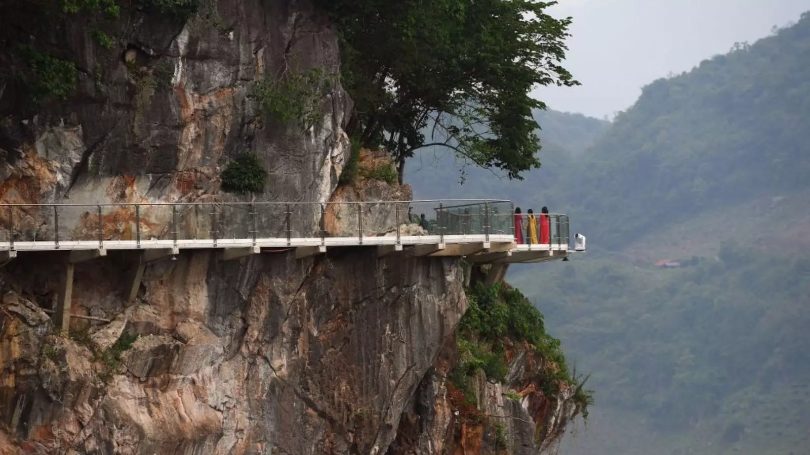 Visitants aturats a la secció de passarel·la del pont de vidre Bach Long del Vietnam contemplant les vistes.