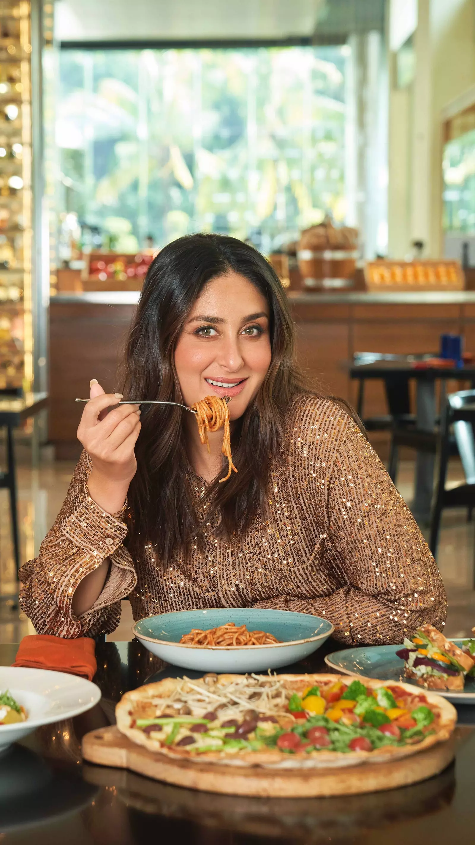 Kareena Kapoor spagettilautasen ja pizzan edessä