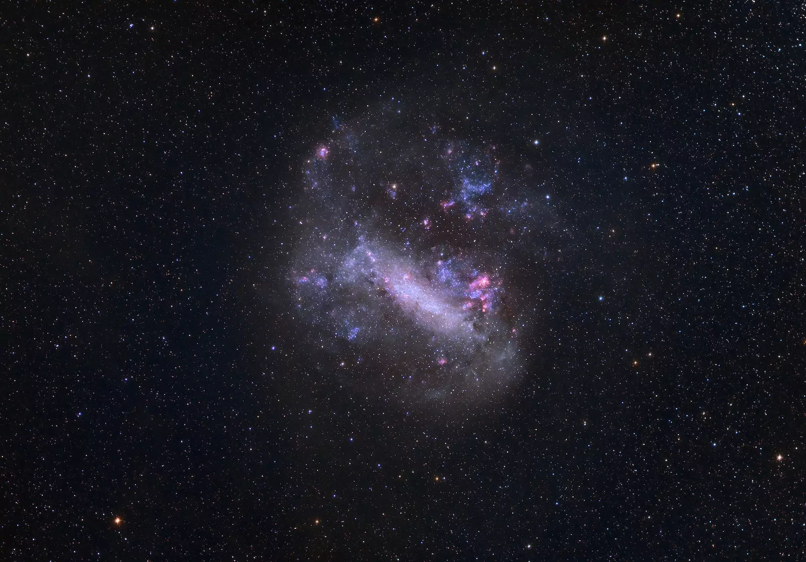 Photograph of the Large Magellanic Cloud a pink and bluish glow in the dark sky