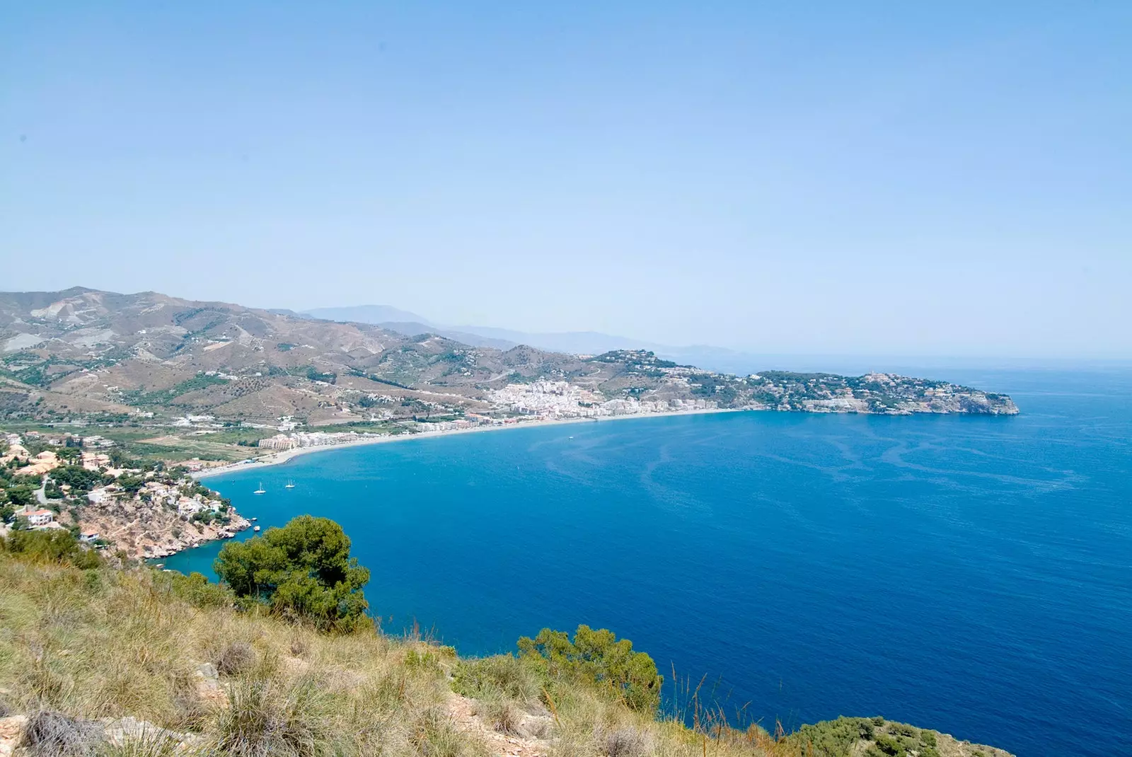 Vista àrea de la forma arrodonida de La Herradura contra el blau del Mediterrani.